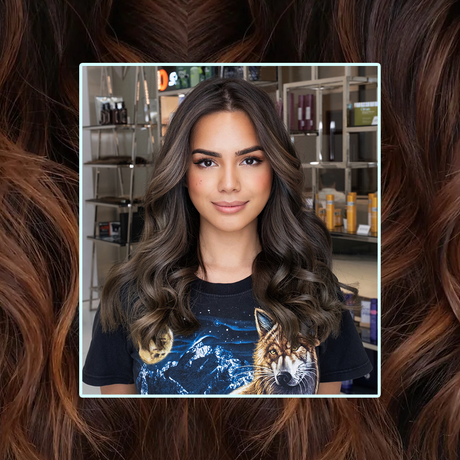 Young girl with a Dark Brown Balayage hair colour standing in front of a wall of haircare products in a salon