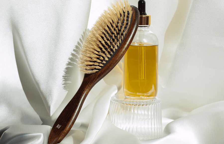 Brush leaning up against a bottle of dry hair treatment oil