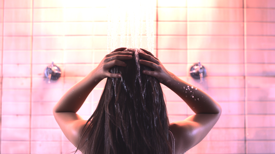 Picture of a woman showering her hair using municipal water. A depiction of how hard water causes hair loss without you even realizing it.