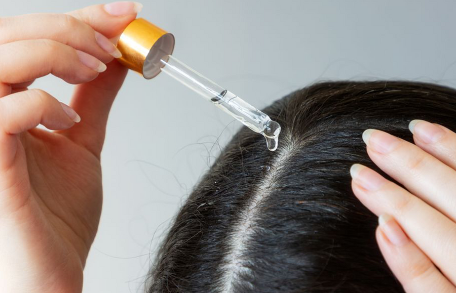 Woman applying Natural Oil to Hair with glass dropper; image is of scalp close up
