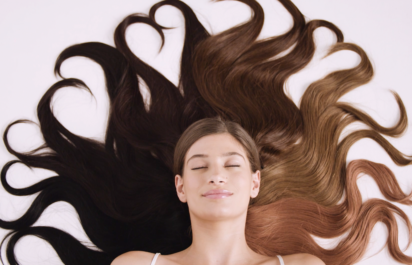 woman lying down with halo hair extensions. Hair is long and growth is due to knowing which oil is best for hair growth and thickness