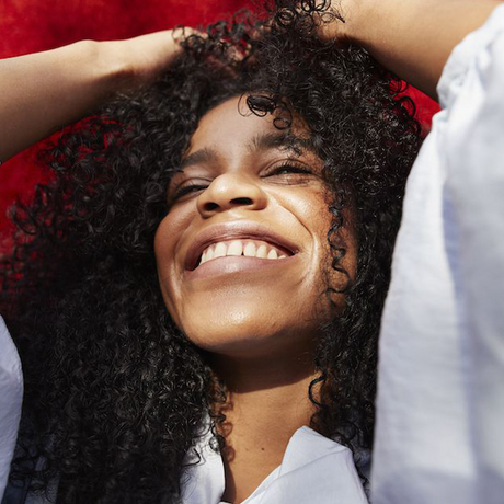 woman who has been dealing with anxiety and hair loss smiling into the sunlight