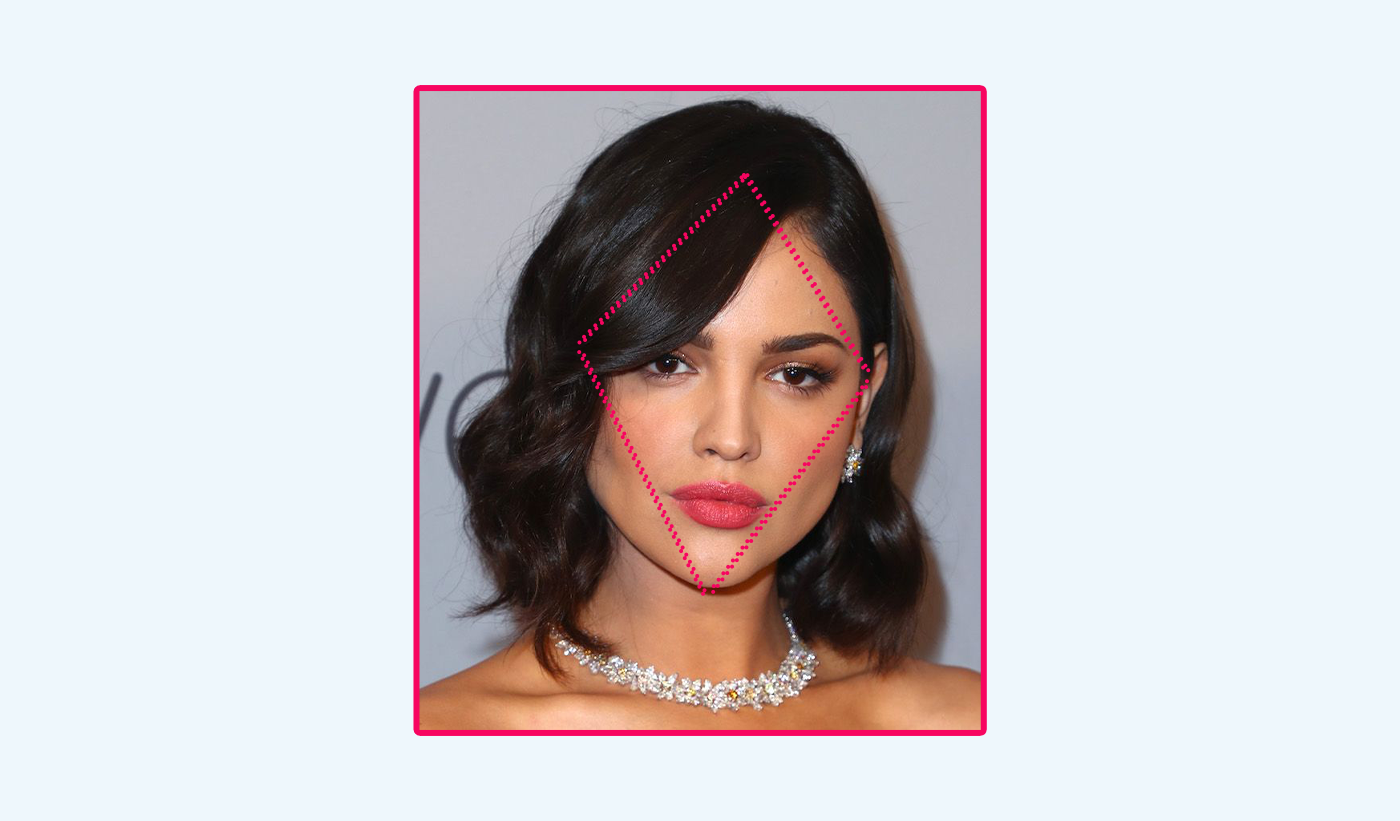 Woman with diamond shaped face and curled hairstyle against a blue background