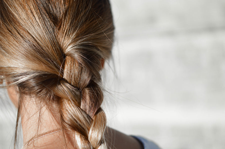 Naturally thicker fuller hair tied up in a plait. Photo taken from the back. Dark blonde hair colour.