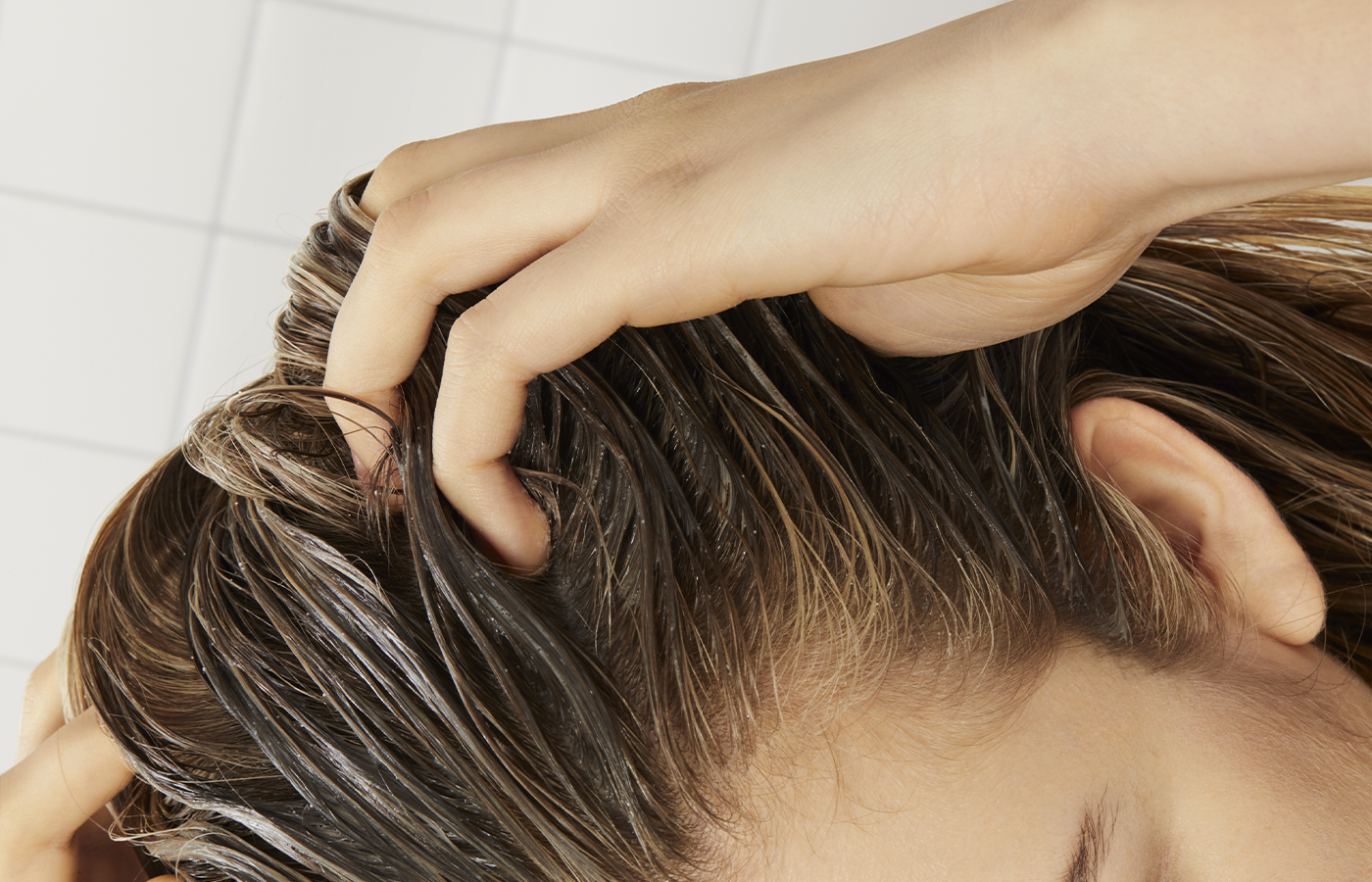 women running fingers through unhealthy scalp which can lead to thinning hair