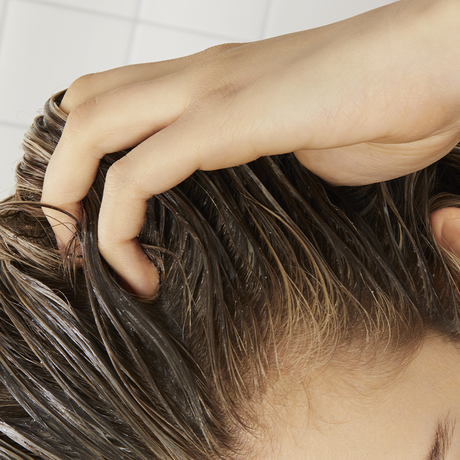 women running fingers through unhealthy scalp which can lead to thinning hair