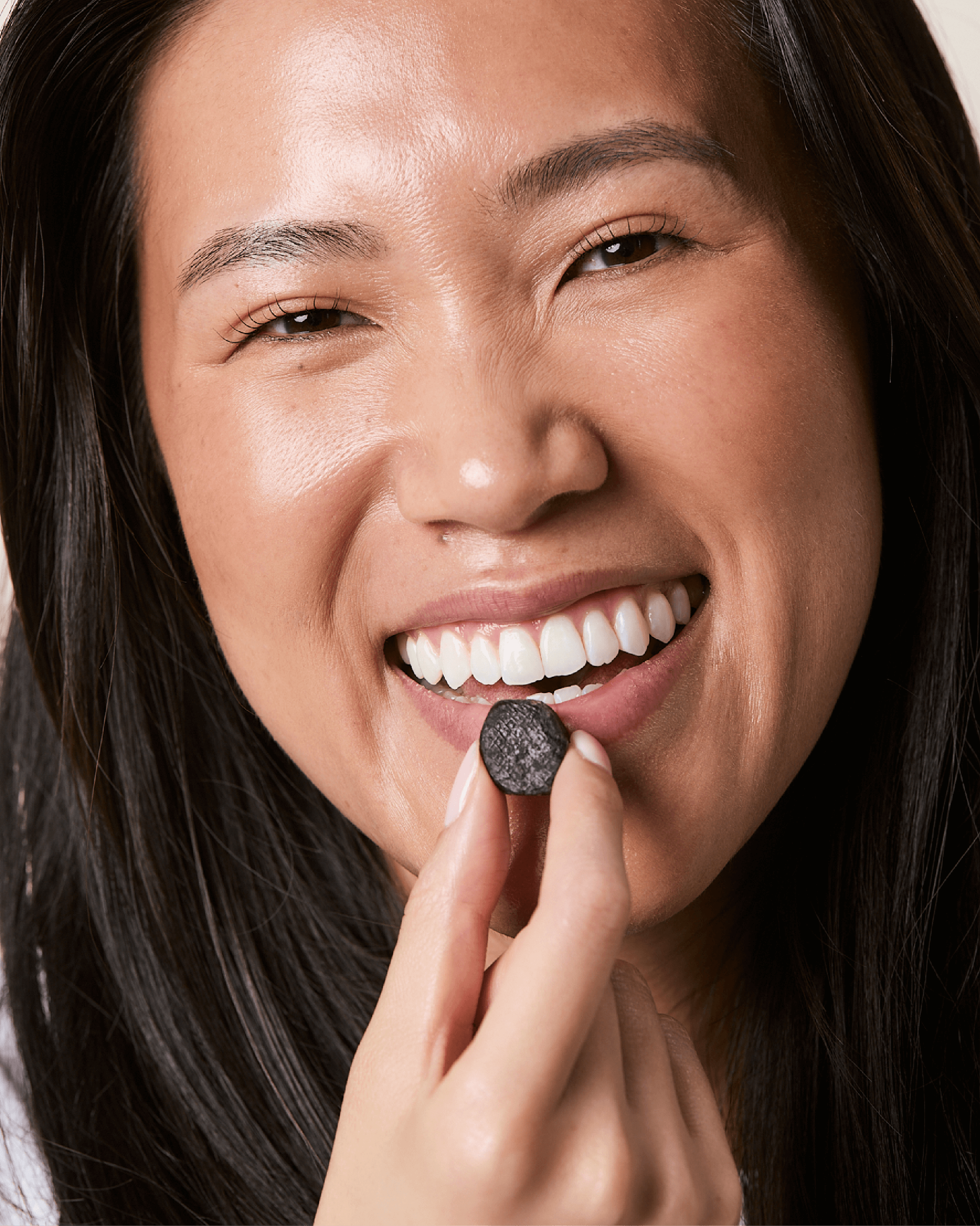 A woman smiles while taking a hair health nutraceutical gummy